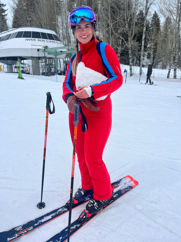 woman wearing tara shakti red one-piece snow suit skiing