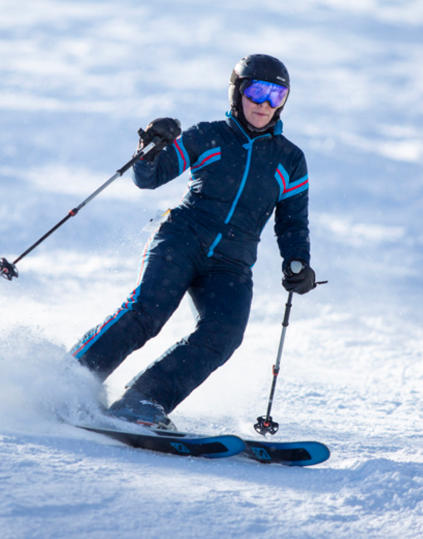 woman wearing tara shakti dark blue bonnie one-piece snow suit skiing