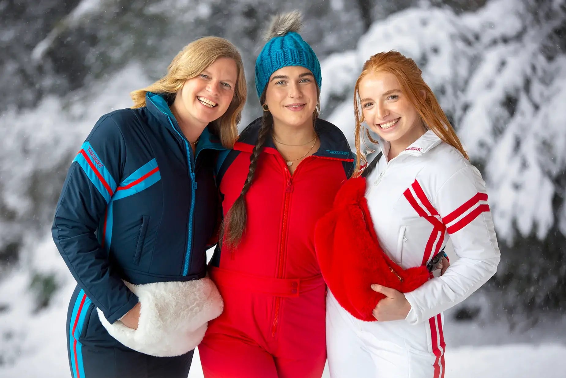 women wearing tara shakti sustainable designer one-piece skiing suits and faux fur fanny packs